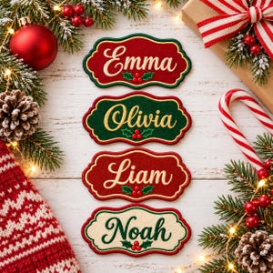 May include: Four scalloped-edge embroidered name tags featuring the names Emma, Olivia, Liam, and Noah. Each tag displays a festive holly berry motif and is stitched in red, green, or cream felt with gold-colored thread borders and lettering.