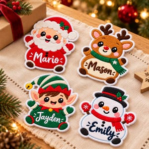 May include: Four embroidered Christmas patches featuring a Santa Claus with the name Mario, a reindeer with the name Mason, an elf with the name Jayden, and a snowman with the name Emily. Each character has a colorful, detailed design.