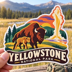 May include: An embroidered patch featuring a brown bison and calf in a landscape with green pine trees, a yellow geyser, and a sunset. The text YELLOWSTONE NATIONAL PARK is printed in white on a dark brown banner at the bottom of the patch.