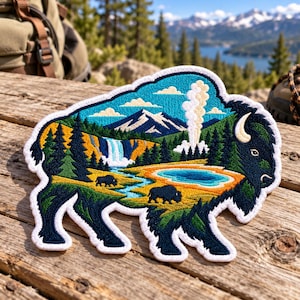 May include: A bison-shaped embroidered patch featuring a detailed landscape scene with a snow-capped mountain, a waterfall, a geyser, and two small bison silhouettes. The design uses vibrant blue, green, yellow, and orange thread colors.