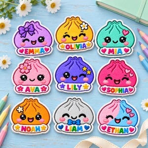 May include: Nine embroidered patches shaped like smiling dumplings, each featuring a unique color and a personalized name: Emma, Olivia, Mia, Ava, Lily, Sophia, Noah, Liam, and Ethan. The patches include decorative elements like bows, flowers, and hearts.