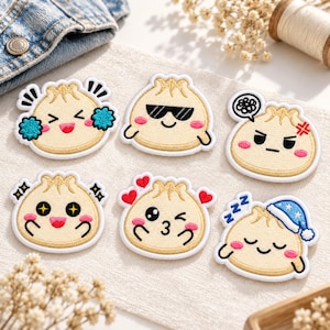 May include: Six embroidered patches shaped like beige dumplings with various facial expressions. One is cheering with blue pom-poms, one wears black sunglasses, one looks angry with a speech bubble, one has star eyes, one is blowing a kiss, and one is sleeping in a blue nightcap.