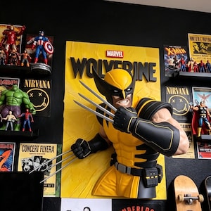 May include: A wall-mounted Marvel Wolverine bust featuring the character in a yellow and black suit with extended silver claws. The figure is set against a yellow rectangular background with the word MARVEL and WOLVERINE in black lettering.