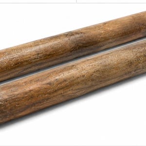 Könnte beinhalten: Zwei zylindrische Holzstäbe mit einer glatten, polierten Oberfläche und einer natürlichen braunen Maserung. Jeder Stab hat eine gleichmäßige, gerade Form mit abgerundeten Enden, die die organische Textur der Holzoberfläche zeigen.
