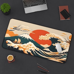 May include: A rectangular desk mat featuring a stylized graphic illustration of a large mountain, a sailing ship, and a crashing wave against a backdrop of a large orange sun, with a beige, dark teal, and orange color palette throughout the design.