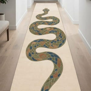 Puede incluir: Una alfombra de pasillo larga y rectangular con base color crema que presenta un gran gráfico de serpiente sinuosa en tonos azules, verdes y naranjas. La alfombra tiene patrones de líneas geométricas en las esquinas y una superficie texturizada.