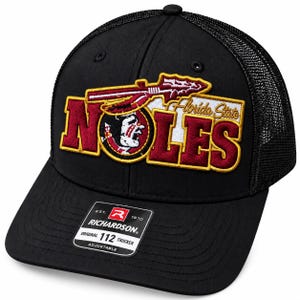 May include: A black trucker hat featuring an embroidered patch with the text NOLES and Florida State in maroon, gold, and white. The patch includes a spear and a profile graphic. A black sticker on the brim reads Richardson Original 112 Trucker.