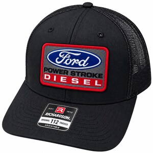 May include: A black trucker hat featuring a rectangular patch with the Ford logo, the text POWER STROKE, and the word DIESEL in red. The hat has a mesh back and a black brim with a sticker that reads RICHARDSON ORIGINAL 112 TRUCKER ADJUSTABLE.