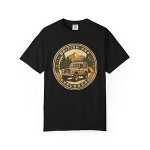 May include: A black short-sleeved t-shirt featuring a circular graphic on the chest. The design depicts a tan 4x4 vehicle parked in front of mountains and pine trees, with a tent nearby. The text "BRITISH 4X4 EXPLORERS" is printed in a circular border.