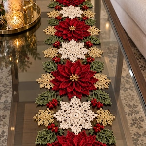Puede incluir: Un camino de mesa de ganchillo largo y rectangular con un patrón repetitivo de flores de pascua de color rojo intenso, copos de nieve blancos y dorados, acentuado con hojas verdes tejidas y pequeñas bayas rojas en todo el diseño.