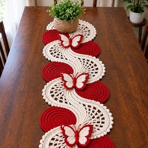 May include: A long, rectangular crochet table runner featuring a repeating wave pattern in cream and deep red. The design incorporates solid red circular motifs and intricate cream-coloured openwork sections, accented by three dimensional butterfly appliqués.