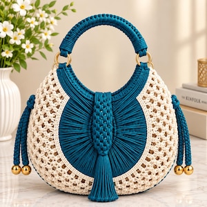 May include: A crescent-shaped handbag crafted from teal and cream-colored cord in a macrame knot pattern. The bag features a circular top handle, a central vertical teal tassel, and two side tassels with gold-toned spherical metal accents.