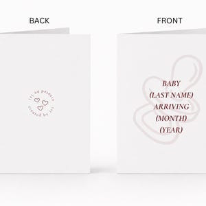 May include: A white folded greeting card shown from the back and front. The back features a small circular logo with three hearts and the text 'created by ivi'. The front displays a light pink pacifier outline with the text 'BABY (LAST NAME) ARRIVING (MONTH) (YEAR)'.