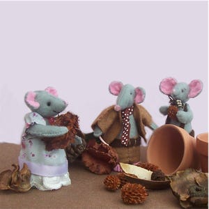 May include: Three handcrafted felt mouse figurines with grey bodies and pink ears. One mouse wears a floral dress with a lavender ribbon, another wears a brown jacket with a polka-dot tie, and the third stands near two small terracotta pots.