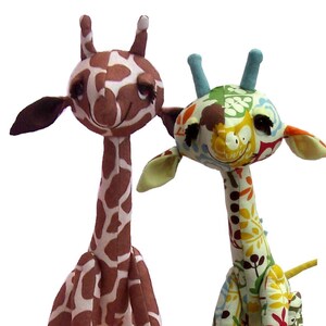 May include: Two plush giraffe toys. The left giraffe features a classic brown and white spotted pattern with dark brown ears. The right giraffe is crafted from a multi-colored fabric with floral and leaf motifs, featuring light blue horns.
