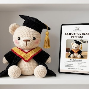 May include: A cream-colored crocheted bear wearing a black graduation cap with a gold tassel and a black graduation gown with a red and gold collar. Next to the bear is a tablet displaying a digital PDF pattern titled Graduation Bear Pattern.