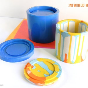 May include: A set of two silicone moulds for making a jar with a lid. The moulds are blue and show the finished product in a colourful abstract design. The text "JAR WITH LID MOLDS SET" is visible in the image.