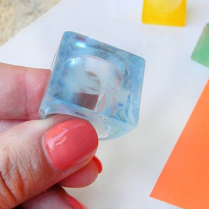 May include: A light blue square ring made of resin. The ring is handmade in Italy.