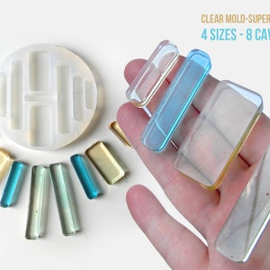 May include: Clear silicone mold with eight rectangular cavities of varying sizes. The mold is shown with finished resin pieces in various colors.