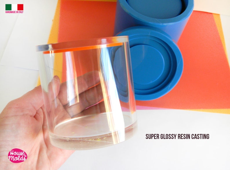 May include: A clear glass cylinder with an orange rim, held in a hand. The cylinder is on top of a blue silicone mould, with the text "SUPER GLOSSY RESIN CASTING" below.