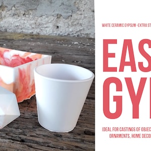 Puede incluir: Material de moldeo de yeso cerámico blanco, etiquetado como "EASY GYP", ideal para hacer objetos, cerámica, adornos y decoración del hogar. La imagen muestra una taza blanca, una forma geométrica y una caja rectangular con un diseño de mármol rosa y blanco.