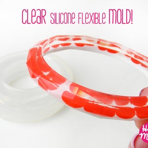 May include: Clear silicone flexible mould for making a red and white patterned bangle bracelet. The mould is shown with a finished bracelet made with it. The bracelet has a geometric design and is made with resin.