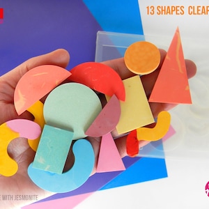 May include: A hand holds 13 colourful shapes made with jesmonite, which are cast in a clear mould. The shapes include circles, squares, triangles, and curved shapes. The mould is labelled "13 Shapes Clear Mould".