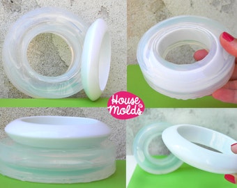 May include: Two clear silicone molds for making resin jewelry. The molds are shaped like rings and are stacked on top of each other. The molds are made by House of Molds.