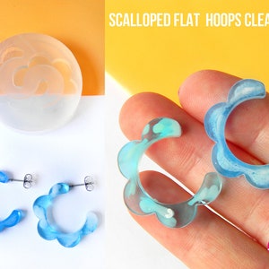 Puede incluir: Molde de silicona transparente para hacer pendientes de aro planos con forma de festón. El molde se muestra con dos pendientes terminados hechos con resina azul.