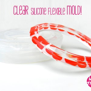 May include: Clear silicone flexible mould for making bracelets. The mould is shown with a red and white heart patterned bracelet made with the mould.