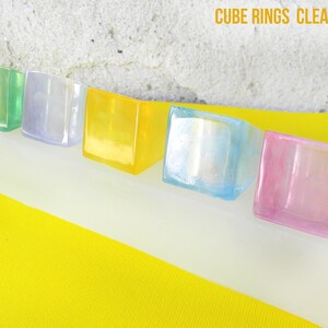 May include: Five clear cube-shaped rings in different colors: green, purple, yellow, blue, and pink. The rings are displayed on a white silicone mold. The text "CUBE RINGS CLEAR MOLD" is visible at the top of the image.
