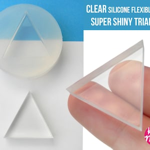 May include: Clear silicone flexible mould for making a triangle shape. The mould is shown in two views, one with the triangle shape inside and one with the mould held in a hand. The text "CLEAR SILICONE FLEXIBLE MOLD SUPER SHINY TRIANGLE!" is visible in the image.