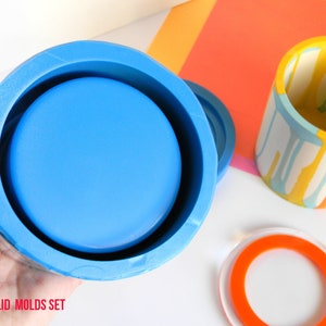 May include: A set of two silicone moulds for making a jar with a lid. The mould is blue and the lid mould is orange. The text "JAR WITH LID MOLDS SET" is visible at the bottom of the image.