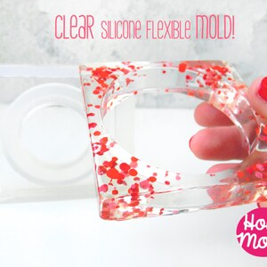 Könnte beinhalten: Eine transparente, flexible Silikonform zum Herstellen eines quadratischen Armreif-Armbands. Die Form wird mit einem mit roten und rosa Glitzer gefüllten Armreif aus Harz gezeigt.