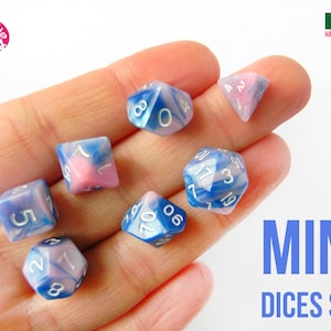 Può includere: Set di sei dadi mini in colori blu e rosa con numeri bianchi. I dadi sono in una mano, e il testo "MINI DICES SET" è nell'angolo in basso a destra dell'immagine.