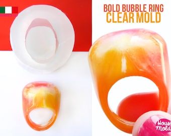 May include: Clear silicone mold for making a bold bubble ring. The mold is shown next to a finished ring made with resin in a yellow, orange, and pink color scheme. The ring is thick and has a large, round opening. The text "BOLD BUBBLE RING CLEAR MOLD" is shown in the upper right corner of the image. The text "House Molds" is shown in the lower right corner of the image.