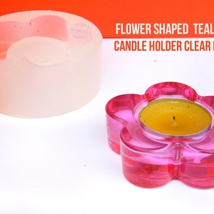 Può includere: Uno stampo in silicone trasparente a forma di fiore per realizzare portacandele per tealight. Lo stampo è mostrato accanto a un portacandele in vetro rosa con una tealight gialla all'interno.
