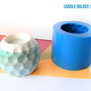 Può includere: Uno stampo in silicone blu per realizzare portacandele. Lo stampo è cilindrico e ha un'apertura rotonda nella parte superiore. Un portacandele finito realizzato con lo stampo è mostrato accanto. Il portacandele è di colore blu chiaro e bianco e ha una superficie testurizzata.