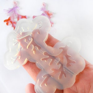 May include: Clear silicone mold for resin casting, featuring a delicate branch design. The mold is flexible and easy to use, perfect for creating unique jewelry or home decor.