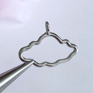 May include: Silver charm in the shape of a cloud with a loop at the top for attaching to a necklace or bracelet.