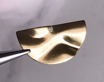 Peut inclure: Un pendentif en métal doré en forme de demi-cercle avec une surface texturée ondulée. Le pendentif a un petit trou en haut pour attacher une chaîne ou une ficelle.