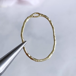 May include: Gold oval ring with a textured surface and a small opening at the top.