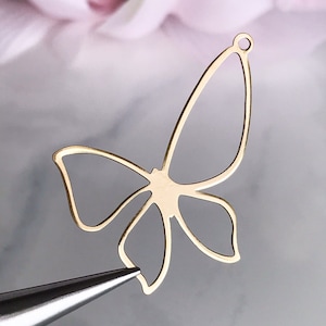 May include: Gold metal butterfly charm with a hole at the top for attaching to jewelry or other crafts.