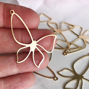 May include: Gold metal butterfly charms with a delicate cutout design. The charms have a hole at the top for attaching to jewelry or other crafts.