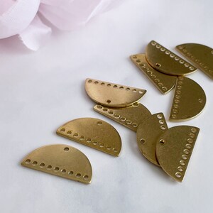 May include: A group of gold half-circle metal charms with a decorative pattern of small circles around the edge.