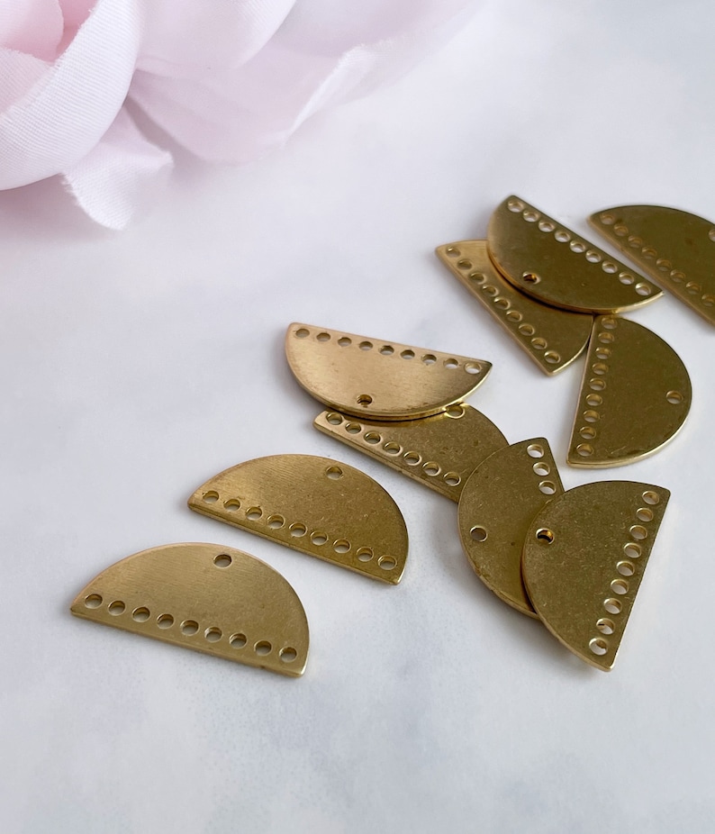 May include: A group of gold half-circle metal charms with a decorative pattern of small circles around the edge.