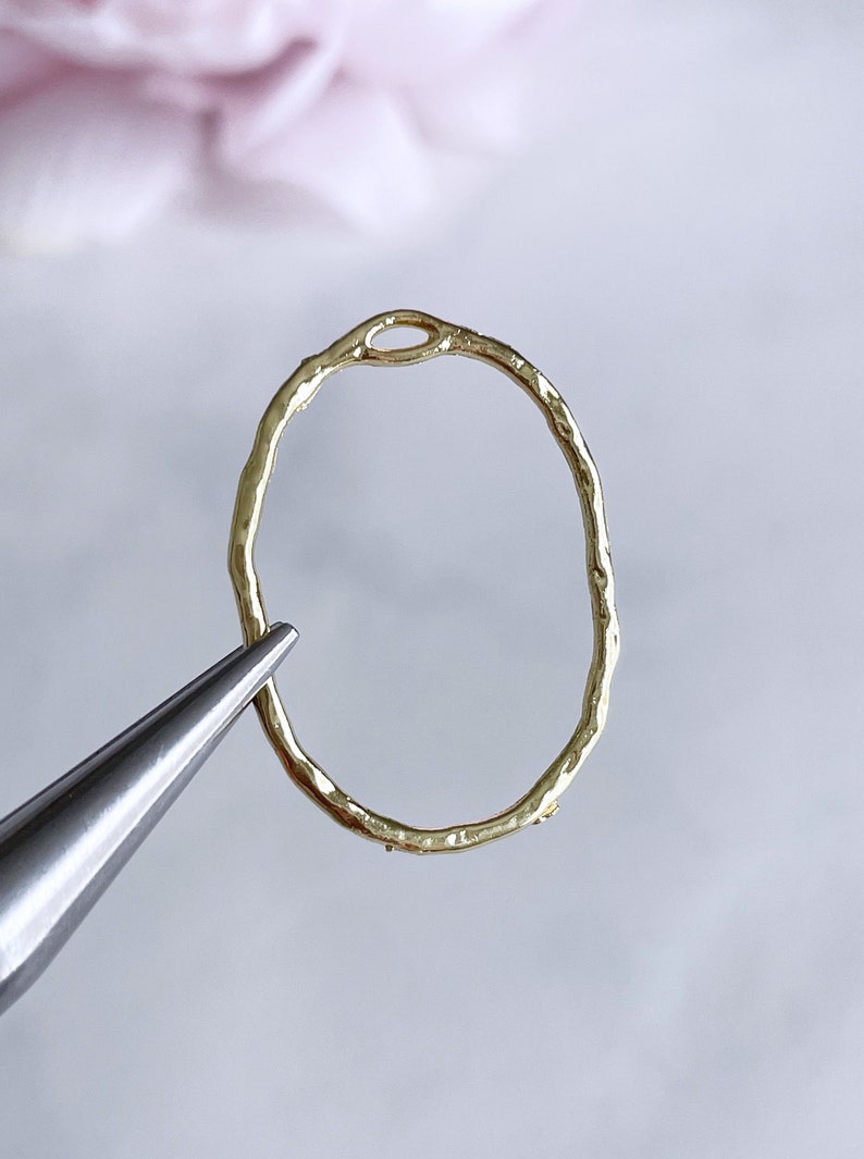 May include: Gold oval ring with a textured surface and a small opening at the top.