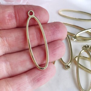May include: Gold oval-shaped metal pendant with a small loop at the top. The pendant is hollow and has a smooth, polished finish.
