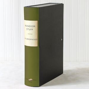May include: A tall, rectangular storage box with a book-like design. The spine is olive green with a cream-colored label that reads "RANDOM STUFF" and "MR ORGANISED". The rest of the box is black. The box is made in England.