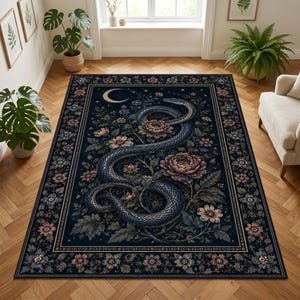 May include: A rectangular area rug featuring a dark navy blue background with a central illustration of a coiled snake surrounded by blooming flowers and a crescent moon. The rug has a decorative border filled with repeating floral patterns.